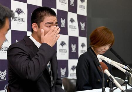 　オリックスからの１位指名で、涙を拭きながら記者会見する延岡学園・藤川敦也。右は母親の七恵さん