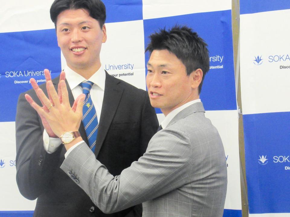 　指名あいさつを受けたドラフト３位の創価大・山崎。青木ＧＭ特別補佐（右）は手の大きさにびっくり？