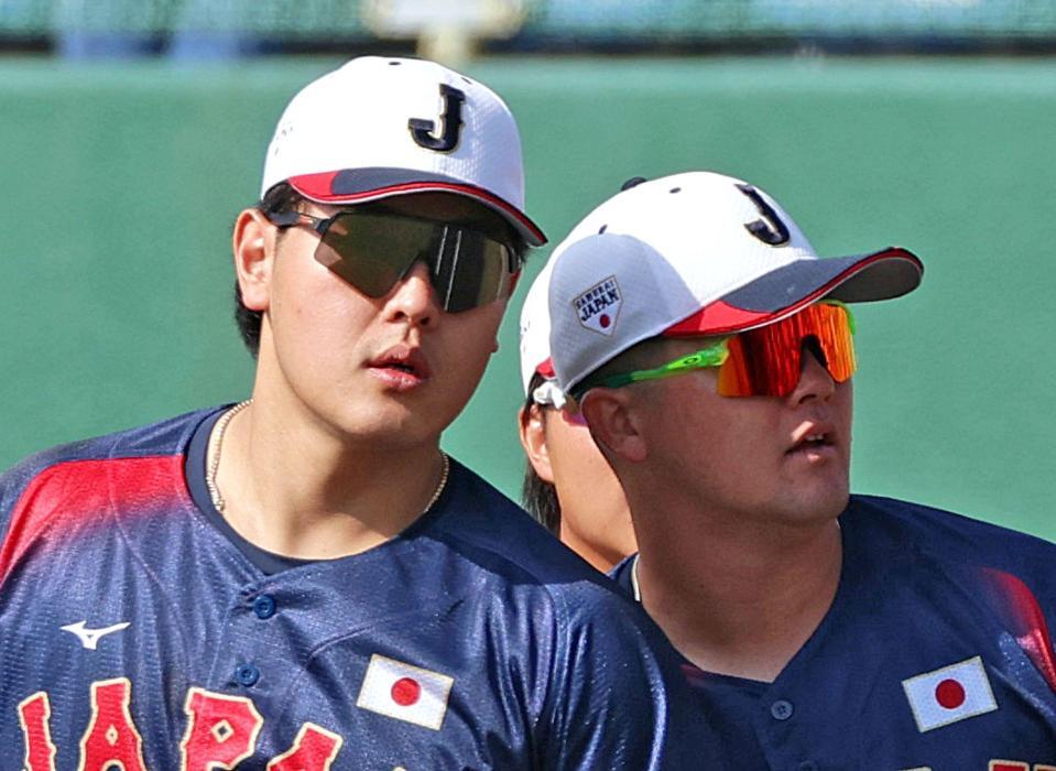 　投内連係で牧（右）に顔を寄せ、ピッチコムの音声を聞く岡本（撮影・立川洋一郎）