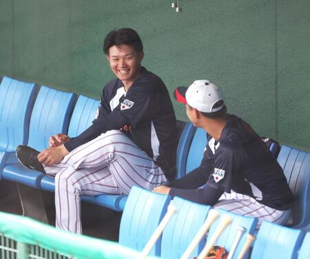 　打撃練習の終了を待って、西川（右）とベンチで談笑する森下（撮影・立川洋一郎）