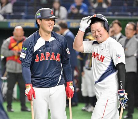 　試合前の打撃練習で牧（右）と談笑する岡本
