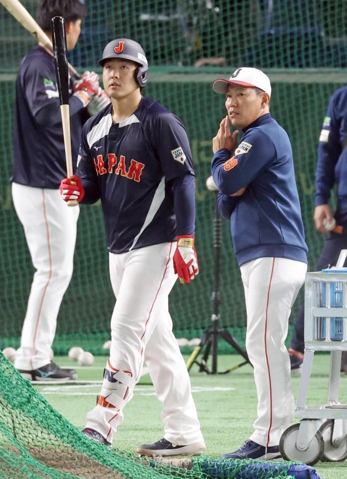 　試合前、井端監督（右）と話す岡本