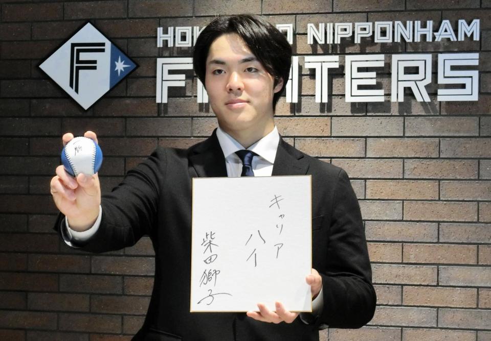 　契約を更改し、来季の目標を記した色紙を手にポーズをとる柴田