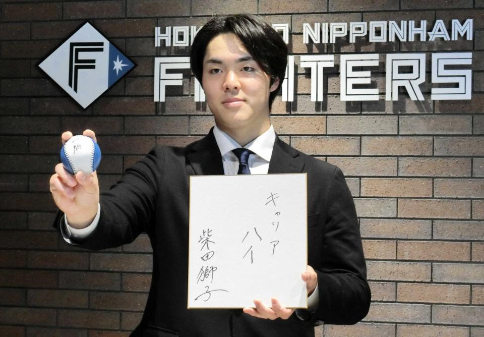 　契約を更改し、来季の目標を記した色紙を手にポーズをとる柴田