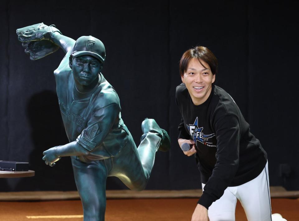 　９００試合登板の等身大立像と同じポーズで記念撮影に応じる宮西（撮影・中島達哉）