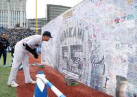 　応援メッセージが書かれたボードを見つめる村上