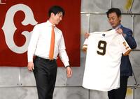 　水野編成本部長（右）から渡される背番号「９」のユニホームを見つめる松本（撮影・堀内翔）