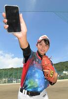 　スマホを手に投球ポーズを決める松本里乃（２１年撮影）