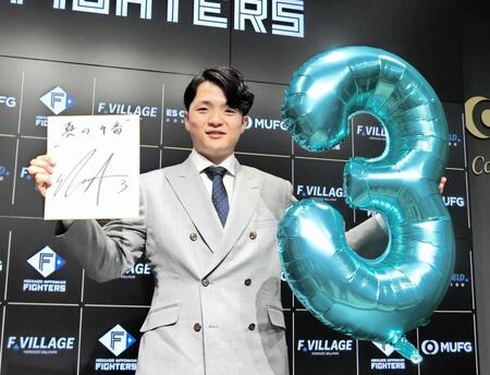 　契約を更改し、来季の背番号３のバルーンと色紙を手にポーズをとる郡司