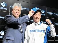 　入団会見に臨み、ユニホーム姿でガッツポーズをする島本（右、左は木田ＧＭ代行）