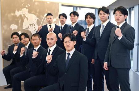 　長嶋茂雄氏の写真パネルの前で写真撮影する（前列右から）冨重、林、松井、河野、知念。（後列右から）竹丸、田和、山城、皆川、小濱、藤