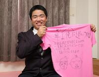 　幼なじみの友人の寄せ書きが書かれたＴシャツを手に笑顔を見せる藤川（撮影・坂部計介）