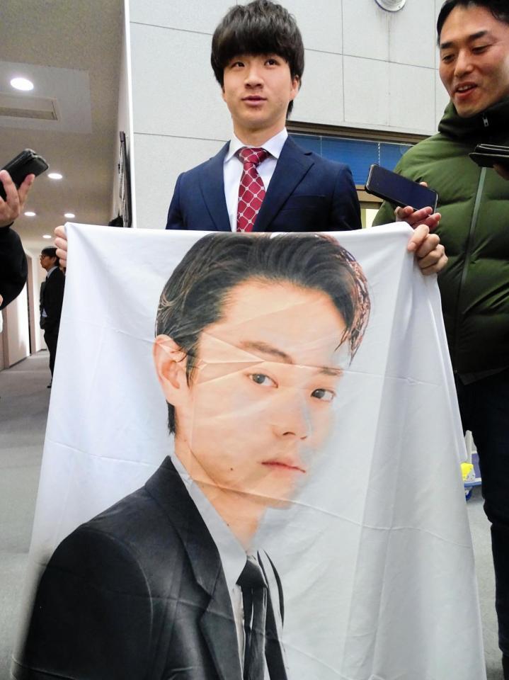 　菅田将暉の特大フラッグを報道陣に披露するロッテ育成３位の杉山（左）