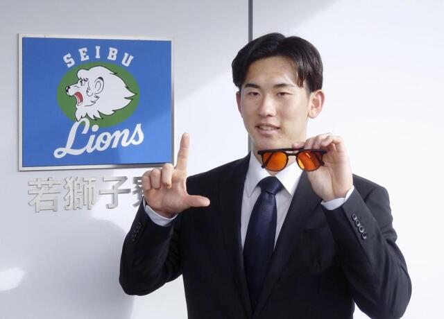 　大学の後輩から贈られた眼鏡を手に、選手寮の前で撮影に応じる小島