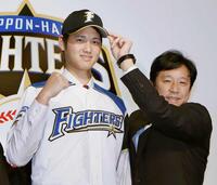 ２０１２年１２月、日本ハムの入団会見で、栗山監督（右）とポーズを取る大谷翔平選手＝札幌市