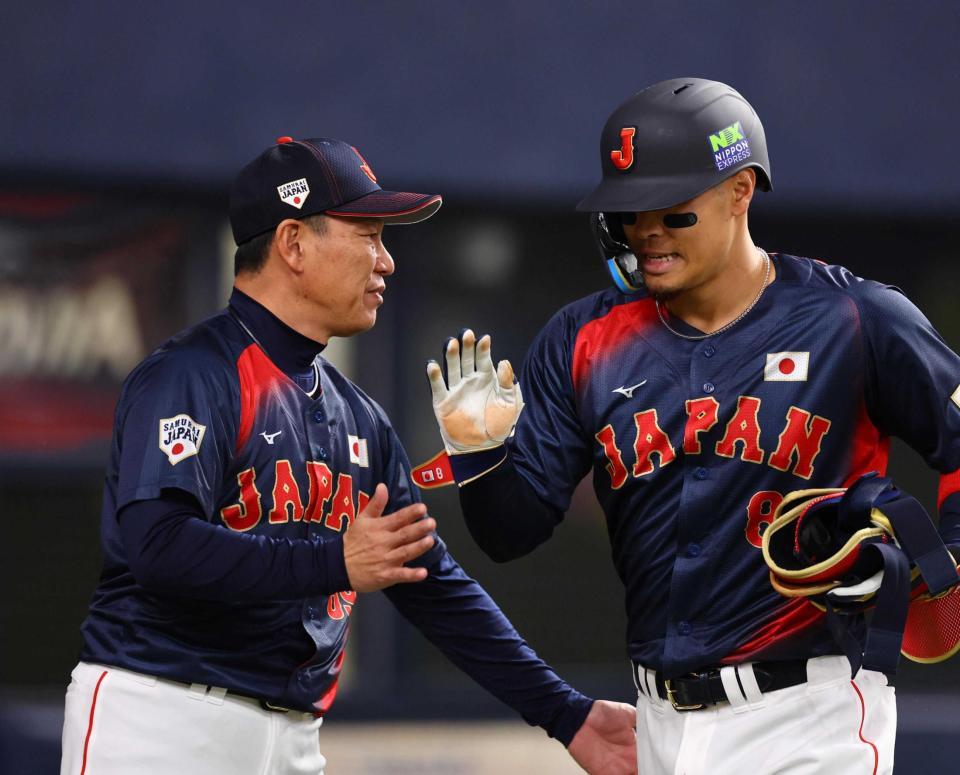 　井端監督（左）に迎えられる佐藤輝＝２５年３月６日