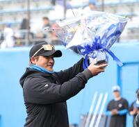 セレモニーで贈呈された花束を掲げる新庄監督（撮影・西岡正）