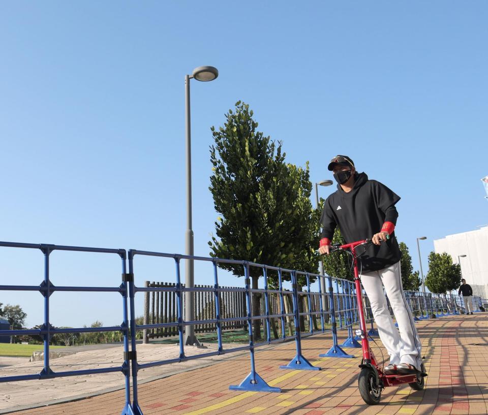 青空の下、電動キックボードで球場入りする新庄監督（撮影・西岡正）