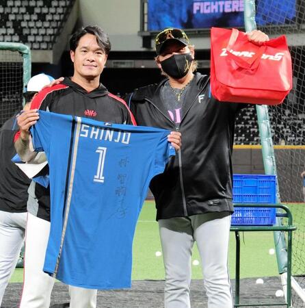 受け取ったプレゼントを手にポーズをとる・新庄監督（右）と林智勝コーチ