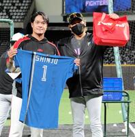 受け取ったプレゼントを手にポーズをとる・新庄監督（右）と林智勝コーチ