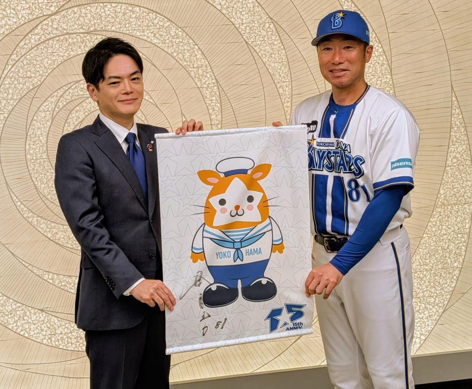 球団誕生15周年を記念したタペストリーを手に、笑顔を見せる相川監督（右）と山中横浜市長