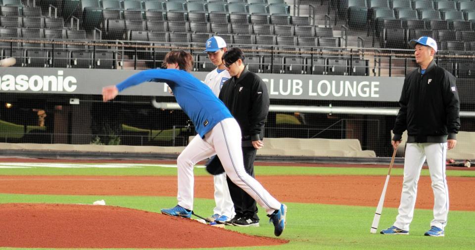 マウンドの傾斜を逆に使って練習する日本ハム・山崎（左）と見守る加藤投手コーチ（右端）