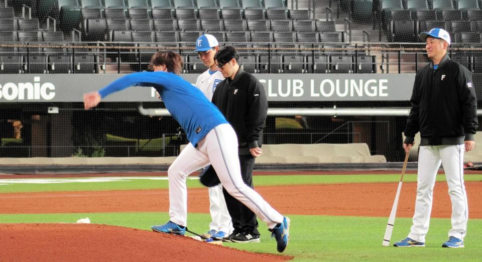 　マウンドの傾斜を逆に使って練習する山崎（左）と見守る加藤投手コーチ（右端）