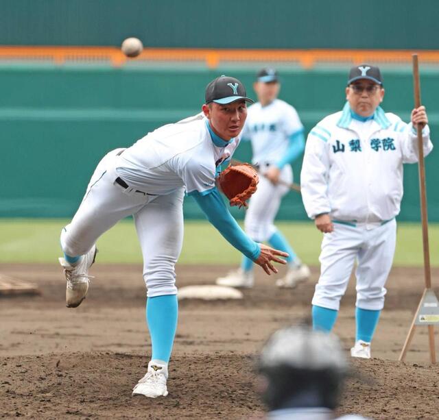 　吉田監督（右）が見守る中、投球練習をする山梨学院・菰田（撮影・中田匡峻）
