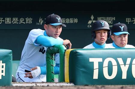ベンチから試合を見つめる山梨学院・菰田（左）