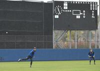 雨の中投球練習する藤浪（左）＝撮影・金居みつよし