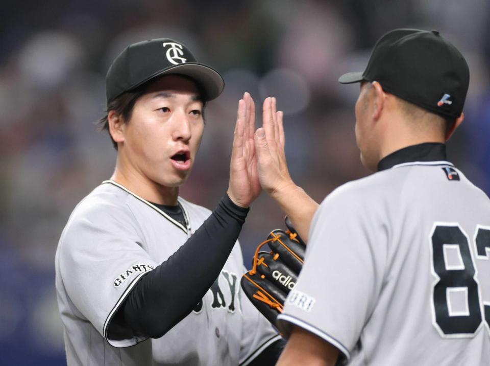 　最後を締め、阿部監督（右）とタッチを交わす大勢（撮影・西岡正）