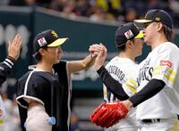 ７回無失点で今季初勝利を挙げ、杉山（右）からウイニングボールを受け取る大津