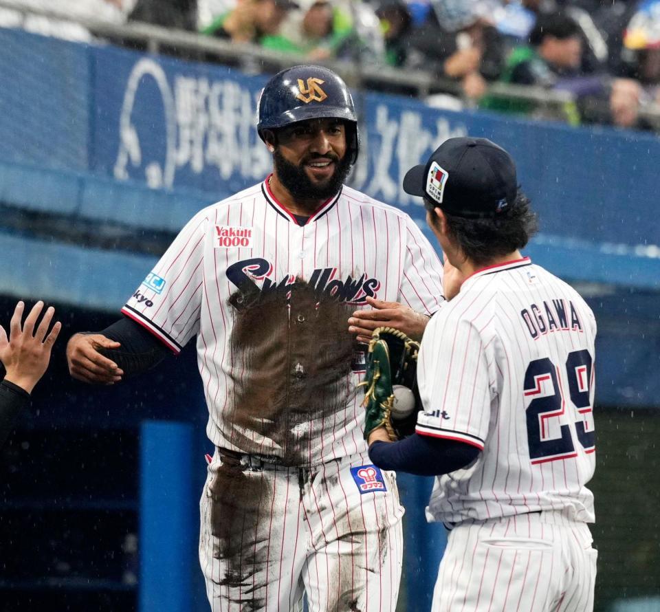 １回、古賀の内野安打と失策で先制の生還をし、小川（右）に迎えられるサンタナ