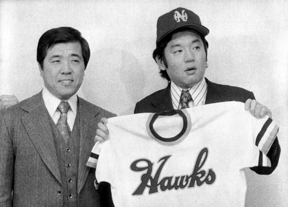 　入団発表で野村克也監督（左）と並び、南海のユニホームを手にする江夏豊＝７５年１２月