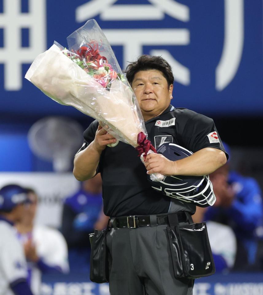 ２０００試合出場を達成し、花束を持つ敷田直人球審（撮影・西岡正）