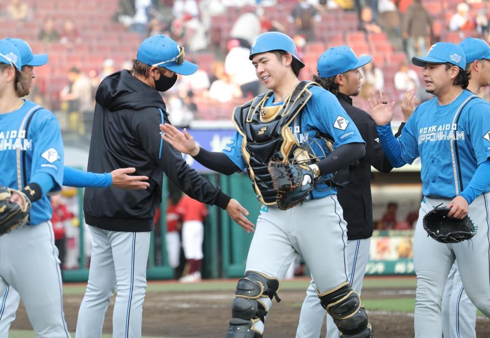 伊藤（右から２人目）と並んでナインを迎える新庄監督）＝撮影・西岡正