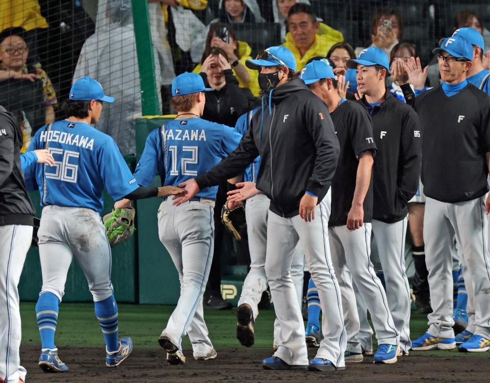 阪神に連勝し、ナインとタッチを交わす新庄監督（中央）＝撮影・立川洋一郎