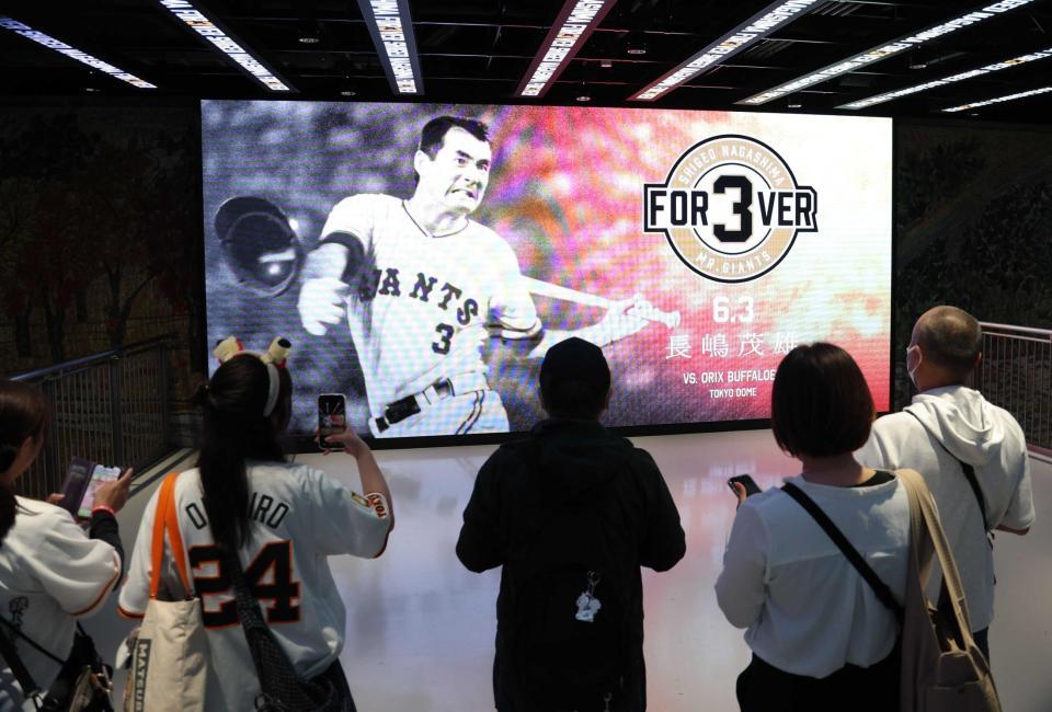 　長嶋茂雄終身名誉監督の現役時代の写真に見入るファン（撮影・西岡正）
