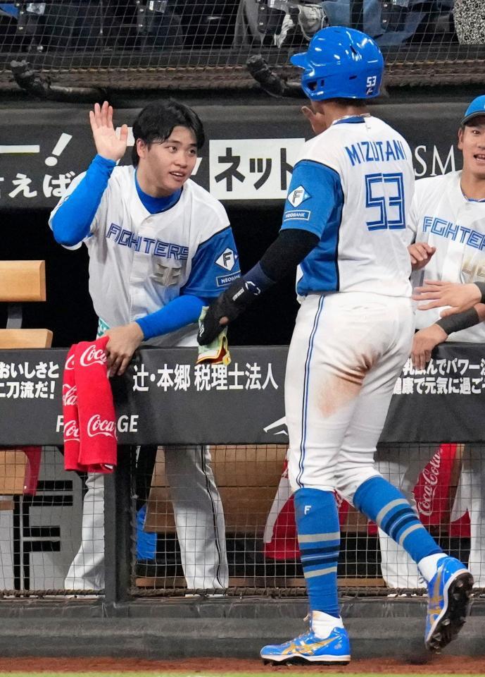 ６回、野村の先制犠飛で生還した水谷（手前）を迎える日本ハムの孫易磊