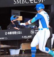 ６回裏、同点ソロを放った万波（右）を迎える新庄監督