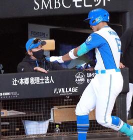６回裏、同点ソロを放った万波（右）を迎える新庄監督