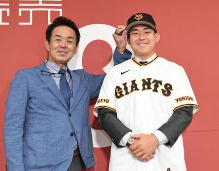 水野編成本部長（左）から帽子をかぶせてもらう小笠原（撮影・佐藤厚）
