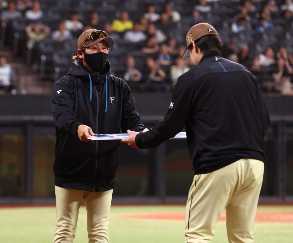 ＮＰＢ通算１００勝を達成した有原（右）に記念ボードを手渡す新庄監督（撮影・中島達哉）