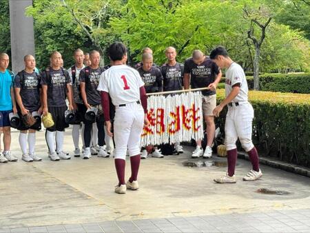 韮崎から千羽鶴を託されお辞儀する山梨学院・菰田（右）