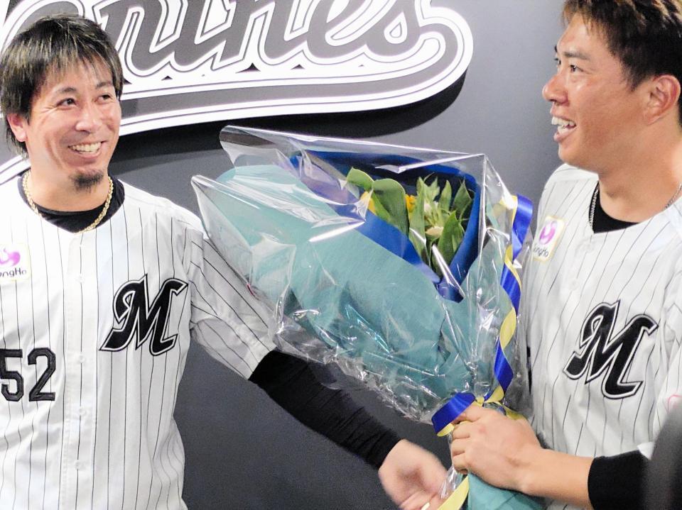 引退会見したロッテの角中（右）は益田から花束を渡され笑顔