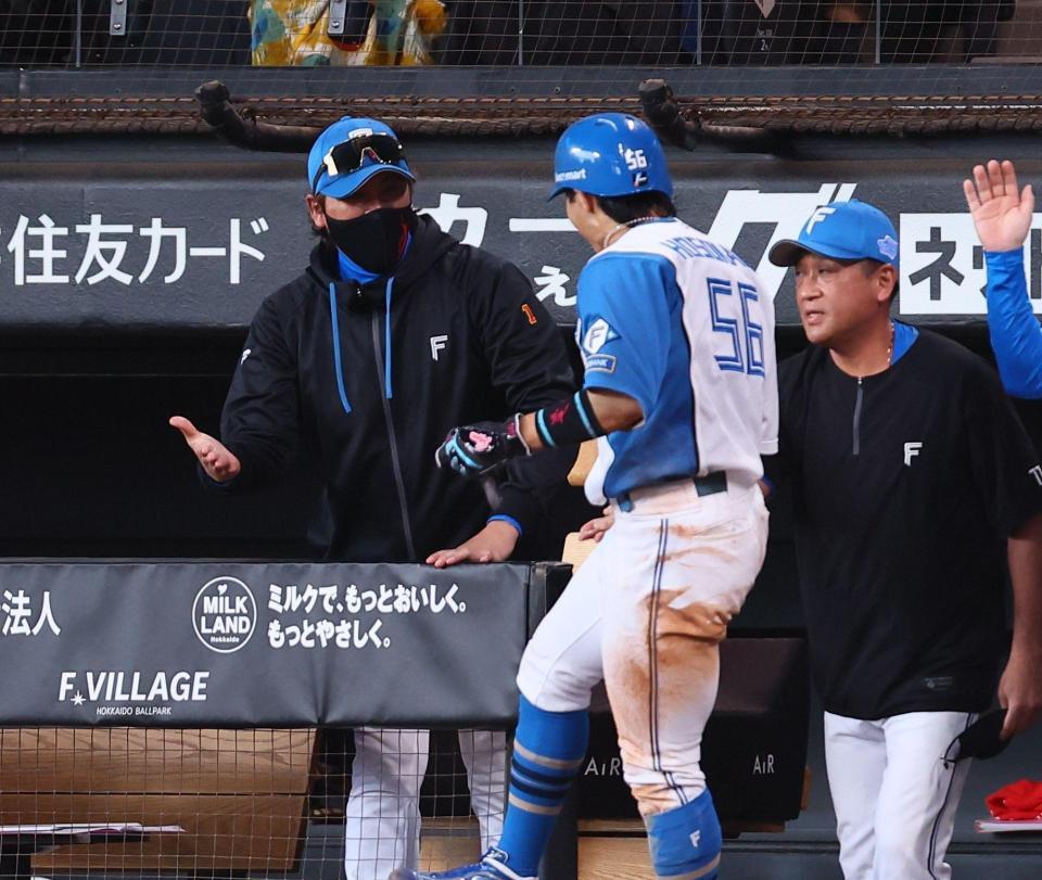 ７回、奈良間の同点犠飛で生還した細川を迎える新庄監督（左）＝撮影・中島達哉