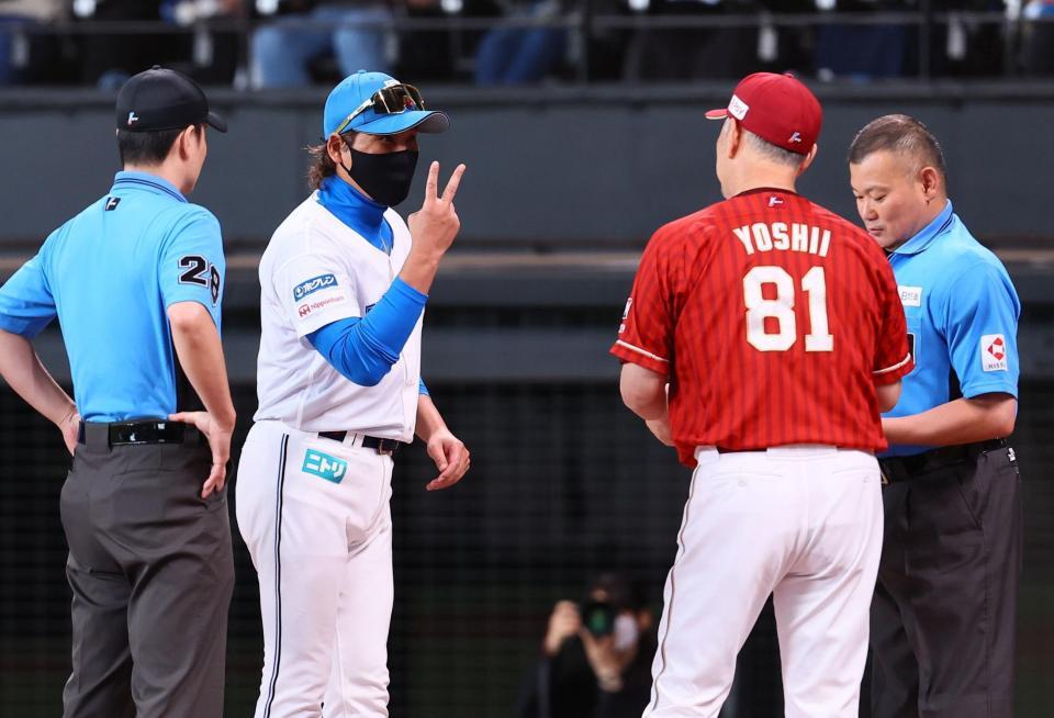 メンバー表を交換の際に吉井監督（８１）にピースサインを示す新庄監督（中央）＝撮影・中島達哉