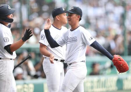 ５回を投げ終え、ベンチ前でナインとタッチを交わす八王子実践・塚原翔太（右）＝撮影・中田匡峻
