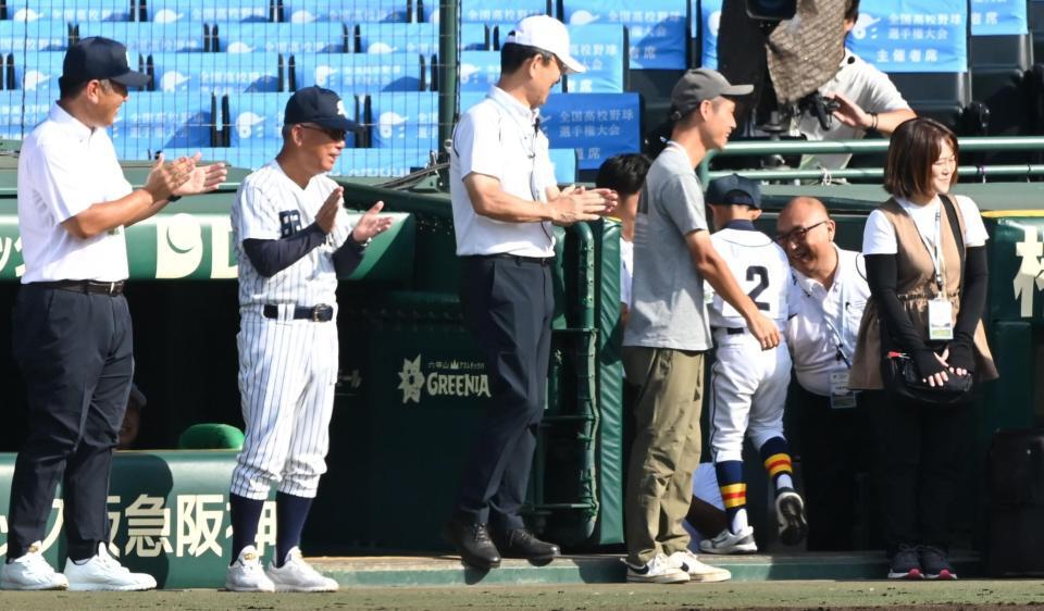 始球式を務めた少年（２）に笑顔で拍手を送る明徳義塾・馬淵史郎監督（左から２人目）＝撮影・高部洋祐
