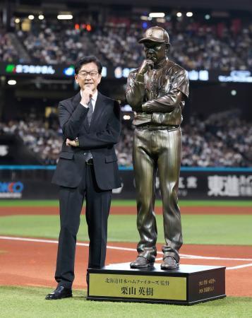 　野球殿堂入りを記念したセレモニーで、自らの立像の横で写真に納まる日本ハム前監督の栗山英樹さん＝エスコンフィールド
